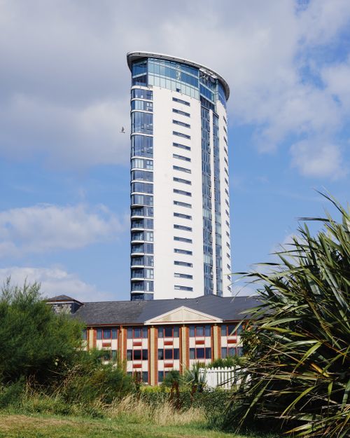 Free Contemporary high-rise building set against a clear blue sky, capturing urban architecture. Stock Photo