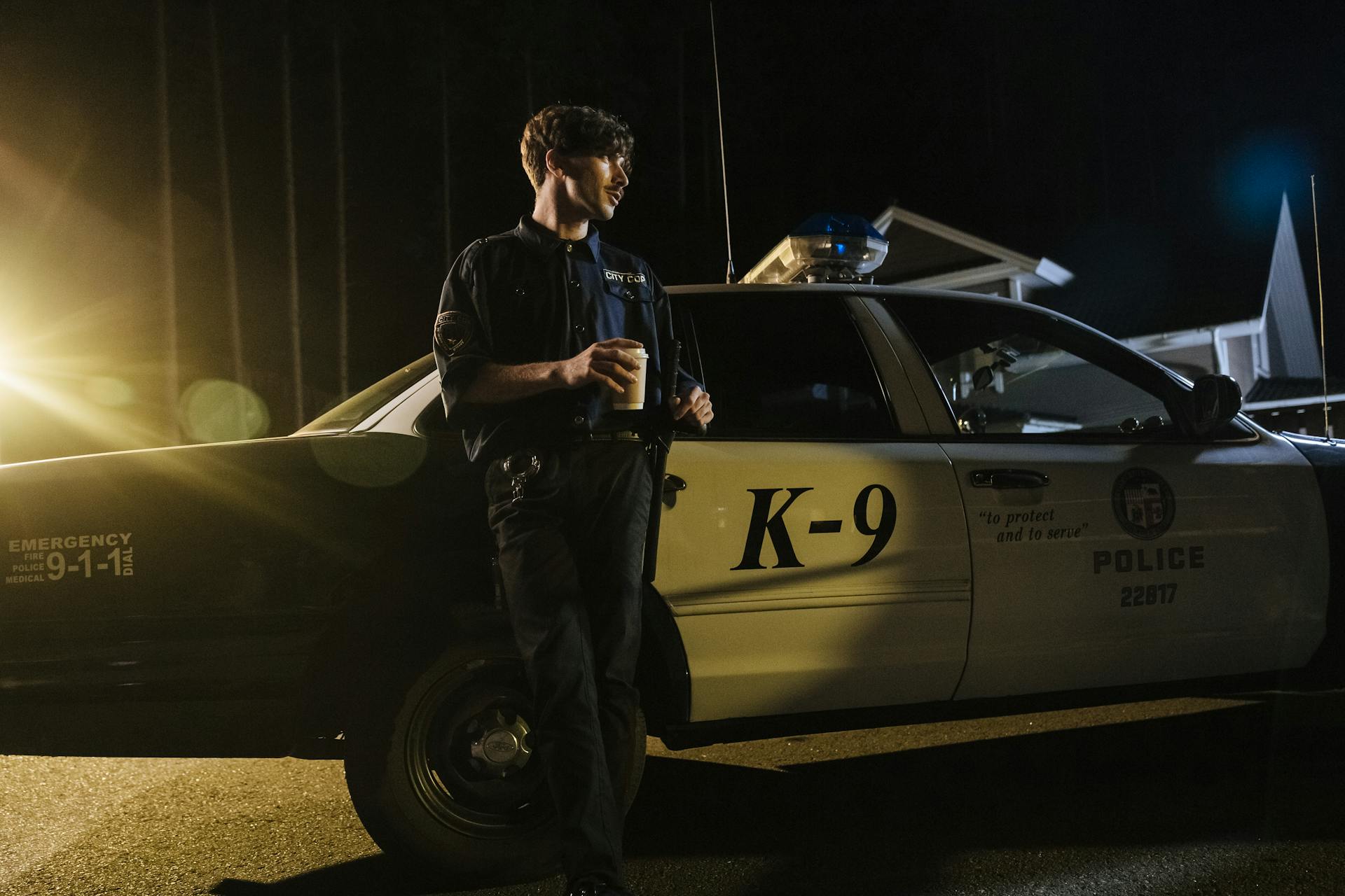 A Policeman Standing Beside Police Car