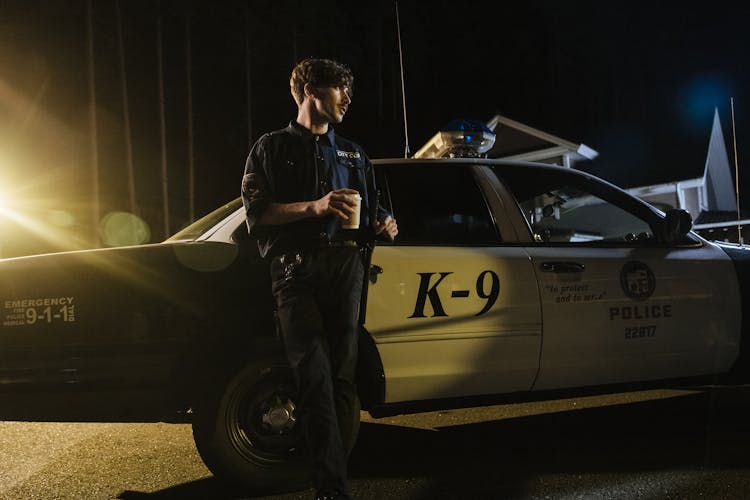 A Policeman Standing Beside Police Car