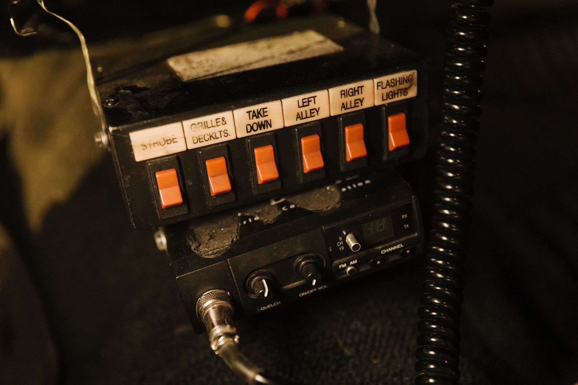 Detailed view of a vehicle's radio system control buttons with labels like strobe and take down.