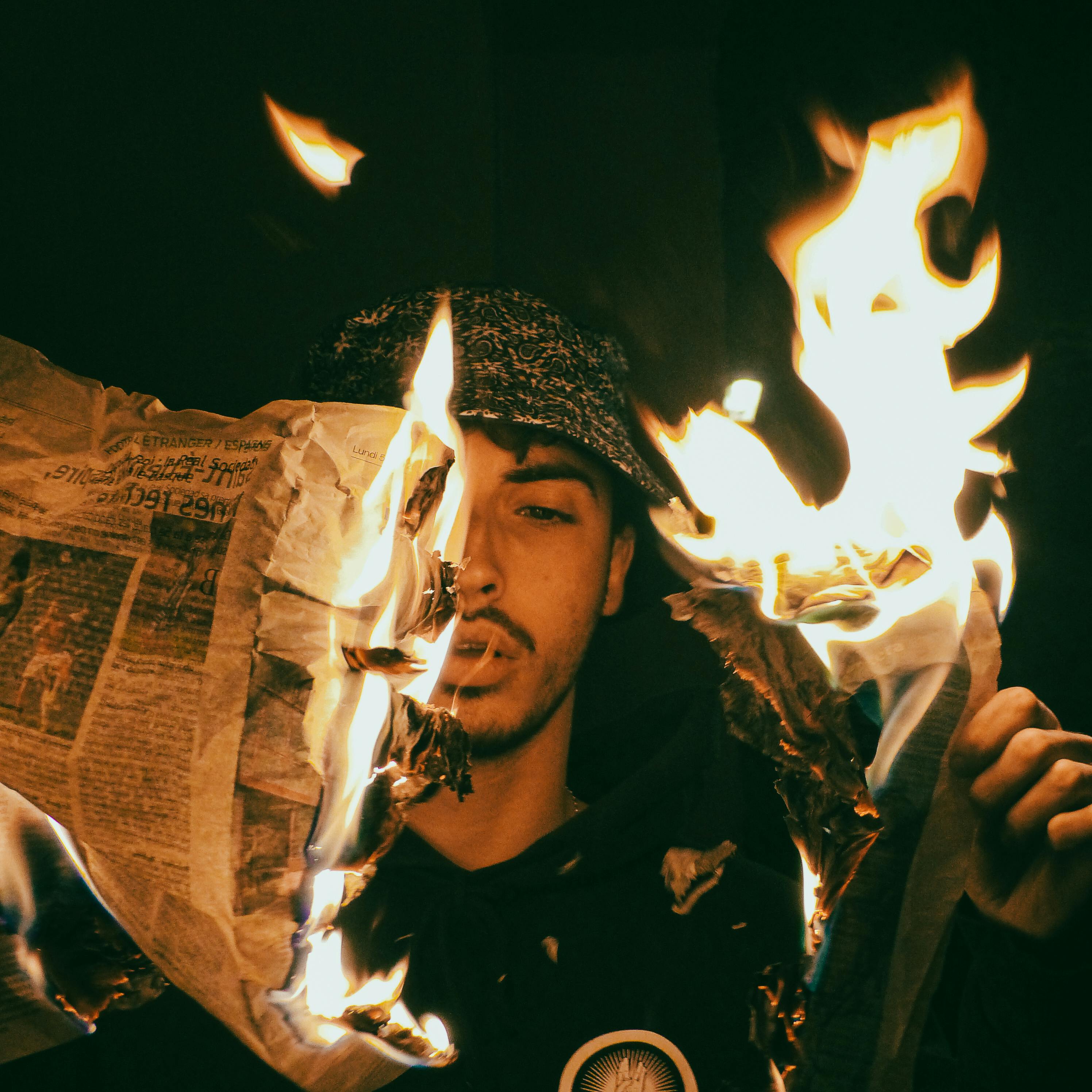 a man holding a newspaper in flames