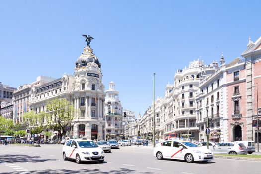 Stunning view of Madrid's landmark Metropolis Building on a sunny day with traffic flowing by.