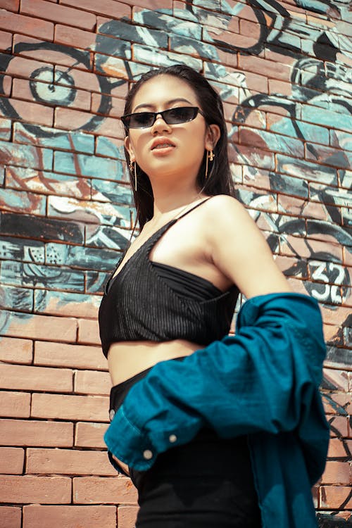 Woman Wearing Sunglasses Standing in Front of Brick Wall