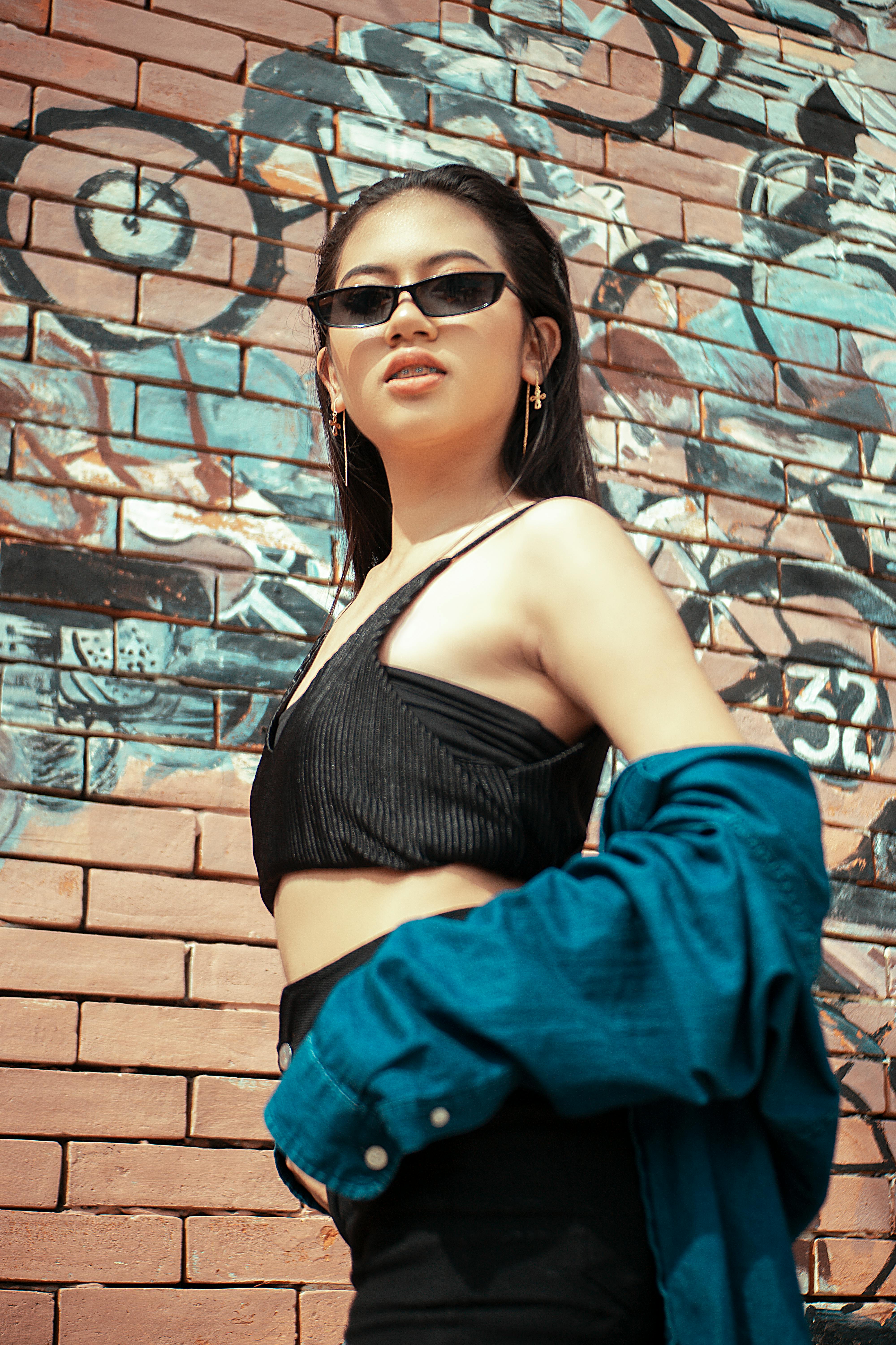 A woman wearing sunglasses standing in front of a wall photo