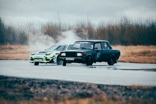 Free Two modified cars drift on a wet asphalt track during an intense motorsport race. Stock Photo