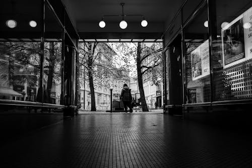 Grayscale Photo of Person Standing outside a Building