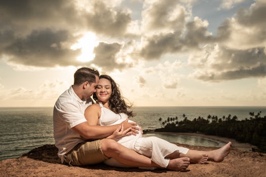 A couple embraces during a maternity shoot against a sunset at Coqueirinho Beach, Brazil.