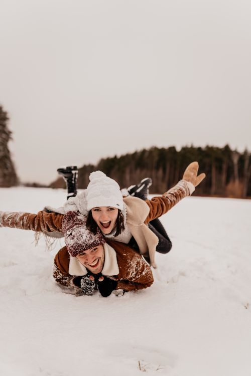 Free A happy couple playfully enjoys the snow, showcasing winter fun and laughter. Stock Photo