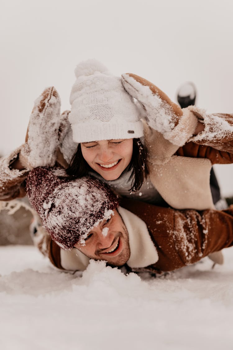 Young Couple Laying And Laughing In Snow 