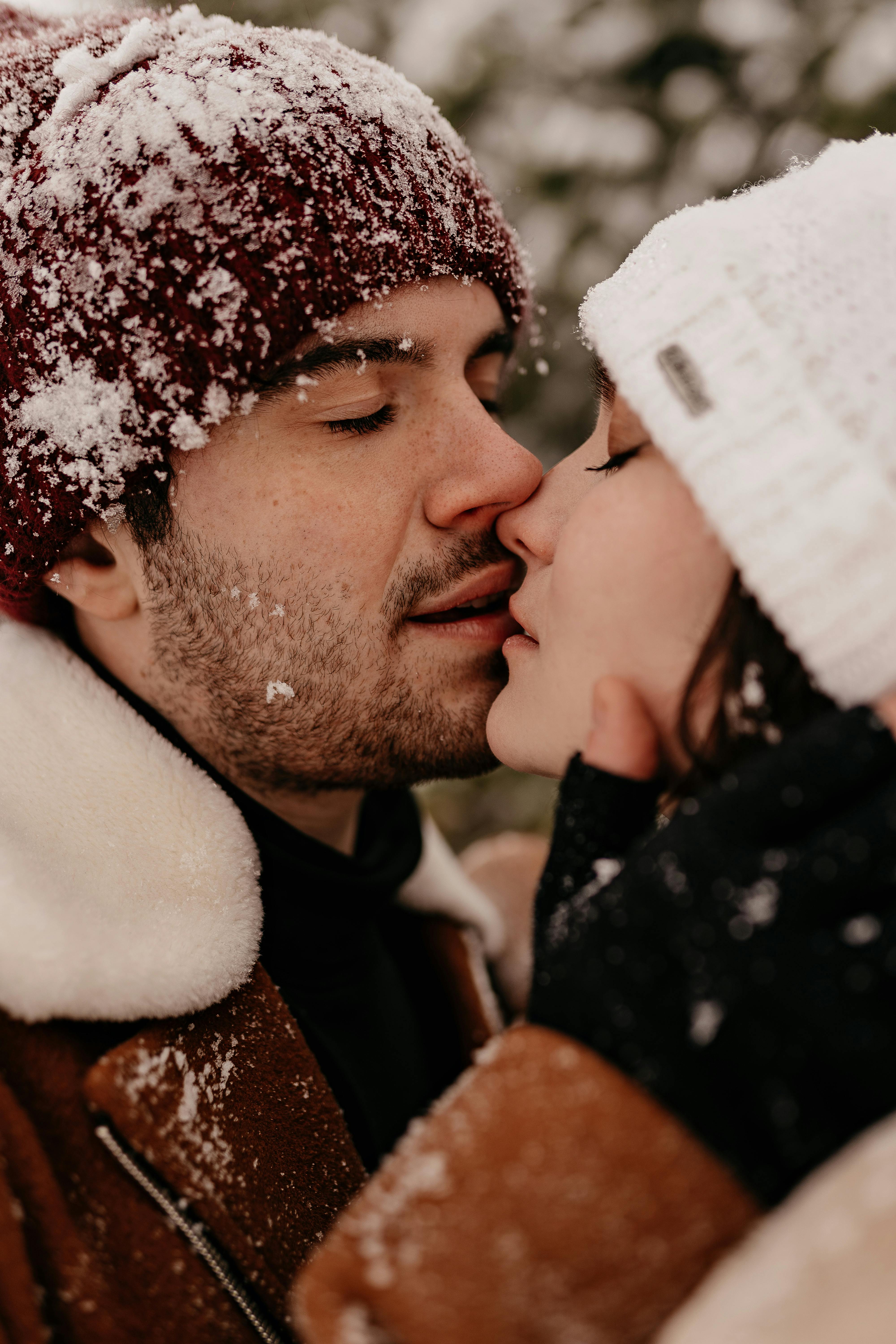 young couple in winter clothing kissing each other with closed eyes