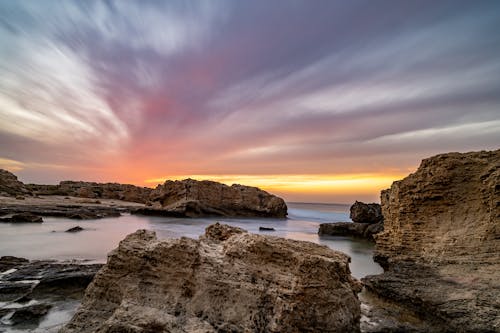 Brown Rock Formations on Sea during Sunset