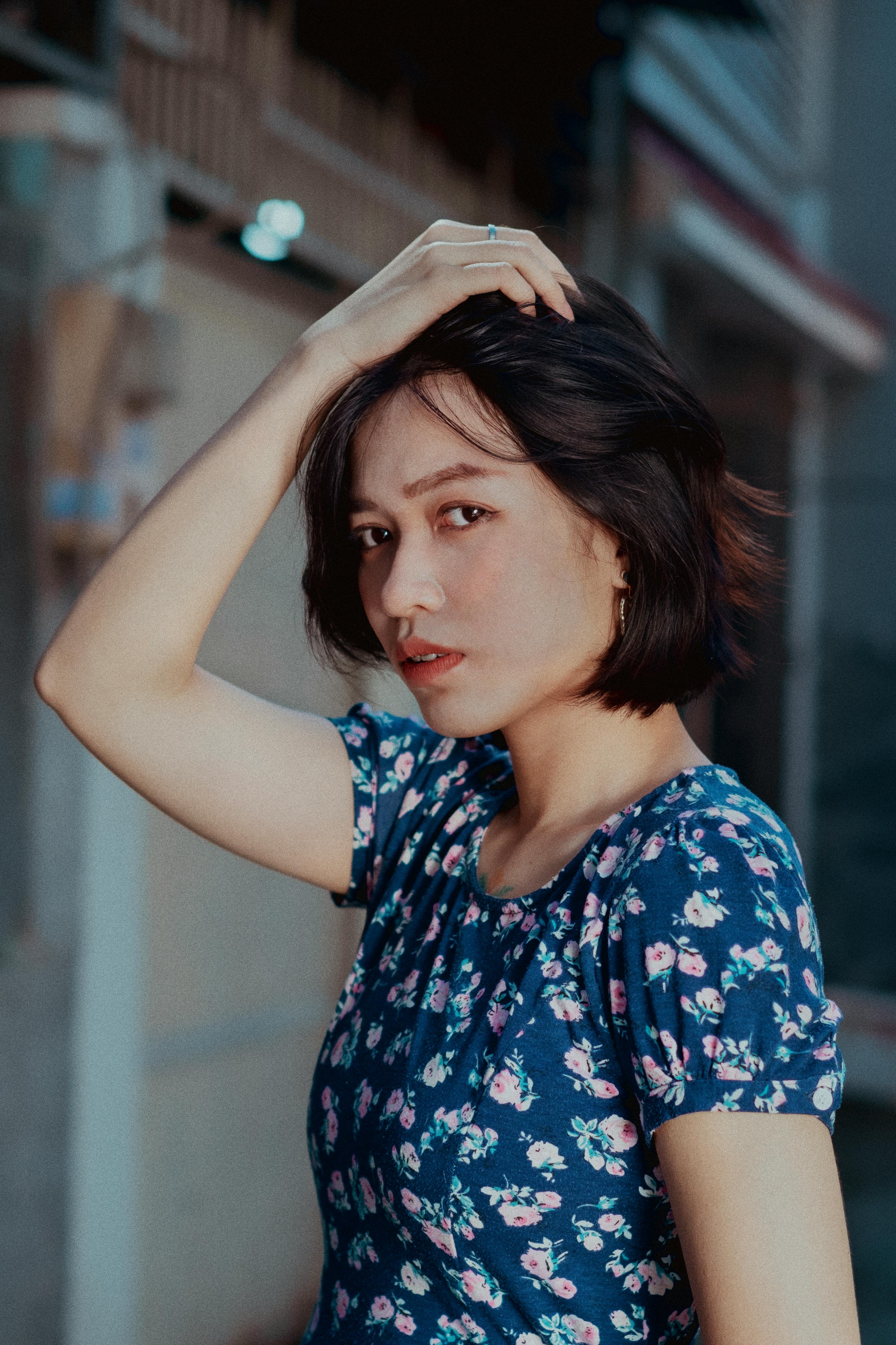Young woman posing in a floral dress, hand on hair, outside in Ho Chi Minh City.