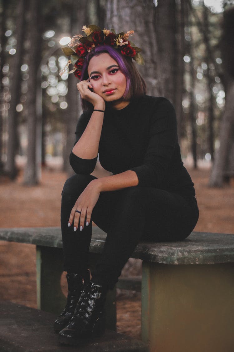 Woman In Black Long Sleeve Shirt And Black Pants Sitting On Table With Hand On Chin 