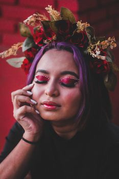 Portrait of a woman with purple hair, adorned with a floral crown, eyes closed in a serene expression.