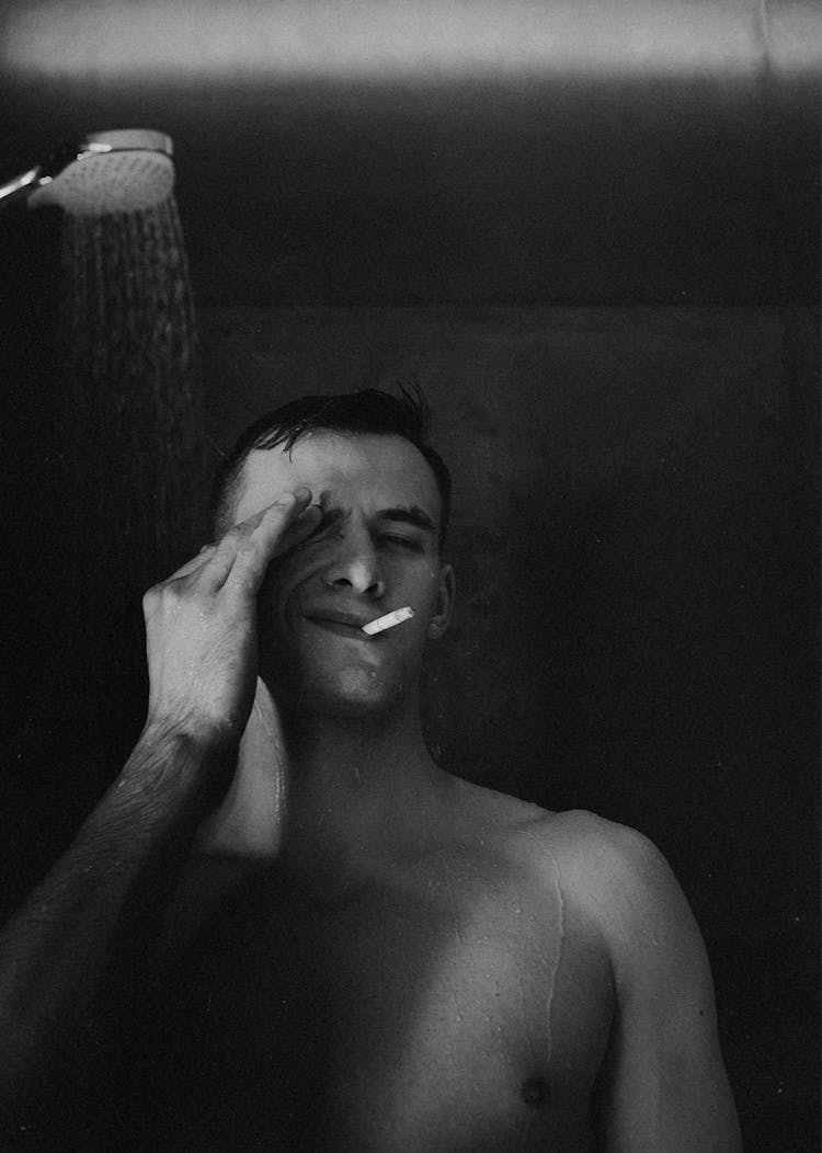 A Grayscale Photo Of A Man Smoking Cigarette While Showering