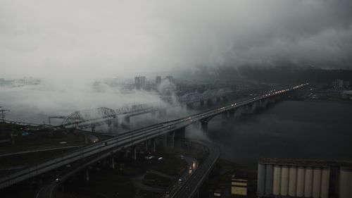 Free Aerial view of foggy cityscape with bridges and highway under cloudy sky. Stock Photo