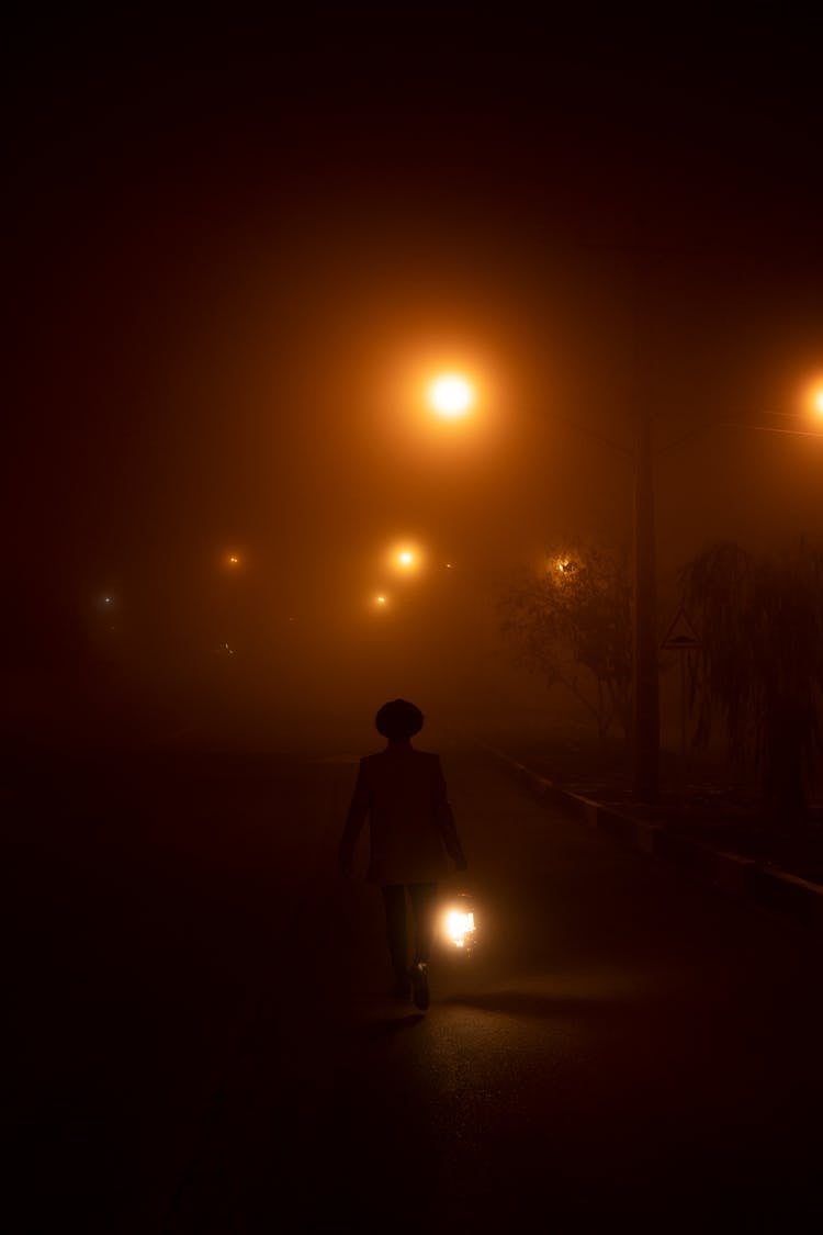 Person In Hat Walking At Night Holding A Lantern