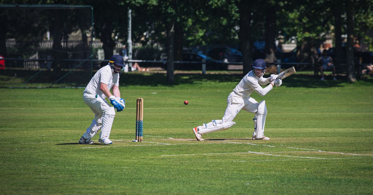 Jos Buttler raising his bat after scoring a century, with Harry Brook celebrating in the background.