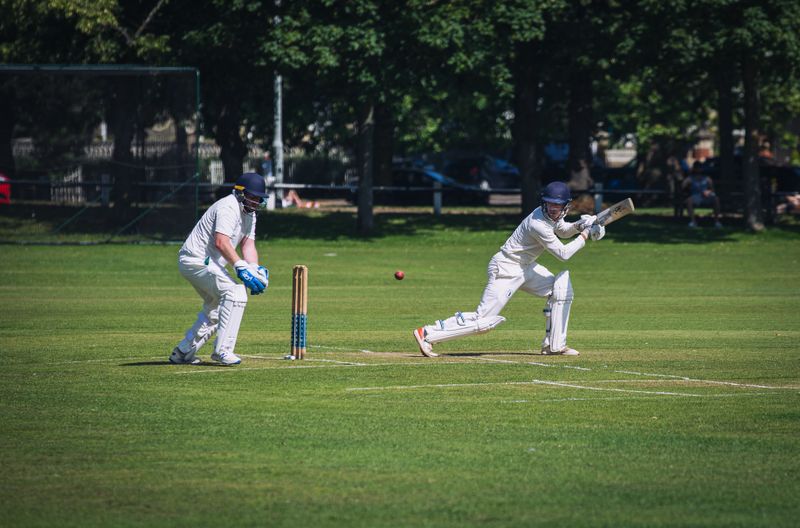 Two cricket players in white uniform on green field