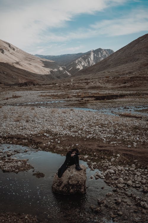 Woman Sitting on a Rock in the Mountains