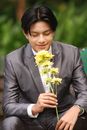 Man in a Gray Suit Smelling Flowers
