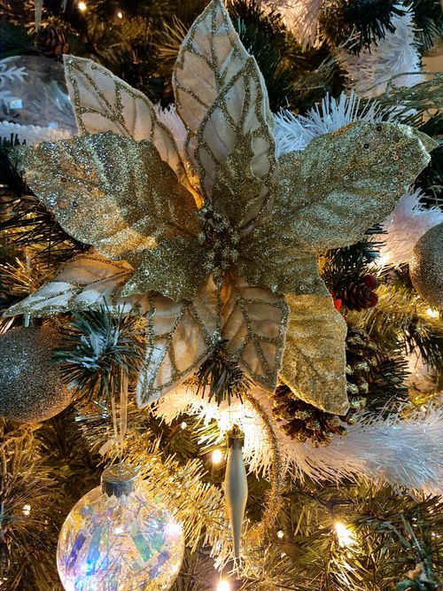 Free Close-up of a glittery poinsettia and ornaments on a Christmas tree. Stock Photo