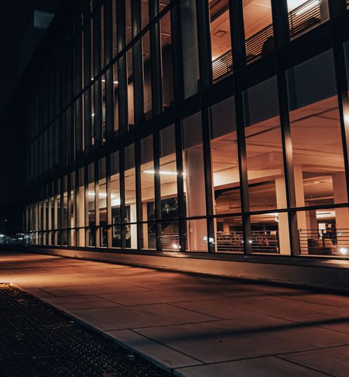 Free Night view of modern building exterior with illuminated glass panels and pavement in Fresno, CA. Stock Photo