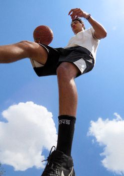 Low angle view of a basketball player in action against a clear sky.