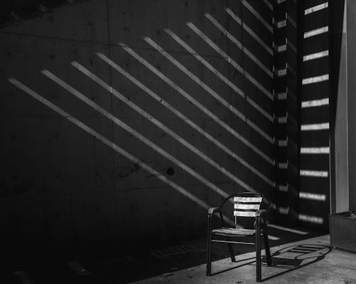 A Grayscale Photo of an Empty Chair Inside the Room