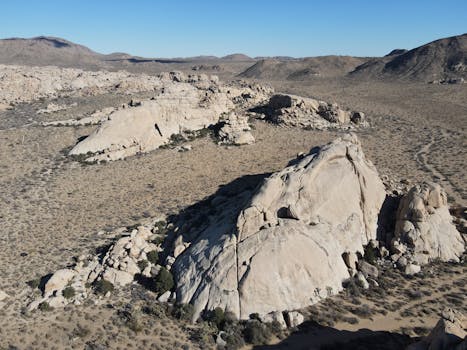 A wide view of rocky geological formations in a desert setting under a clear blue sky.