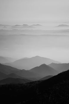Black and white photo of misty mountain valleys creating a serene and abstract scenic view.