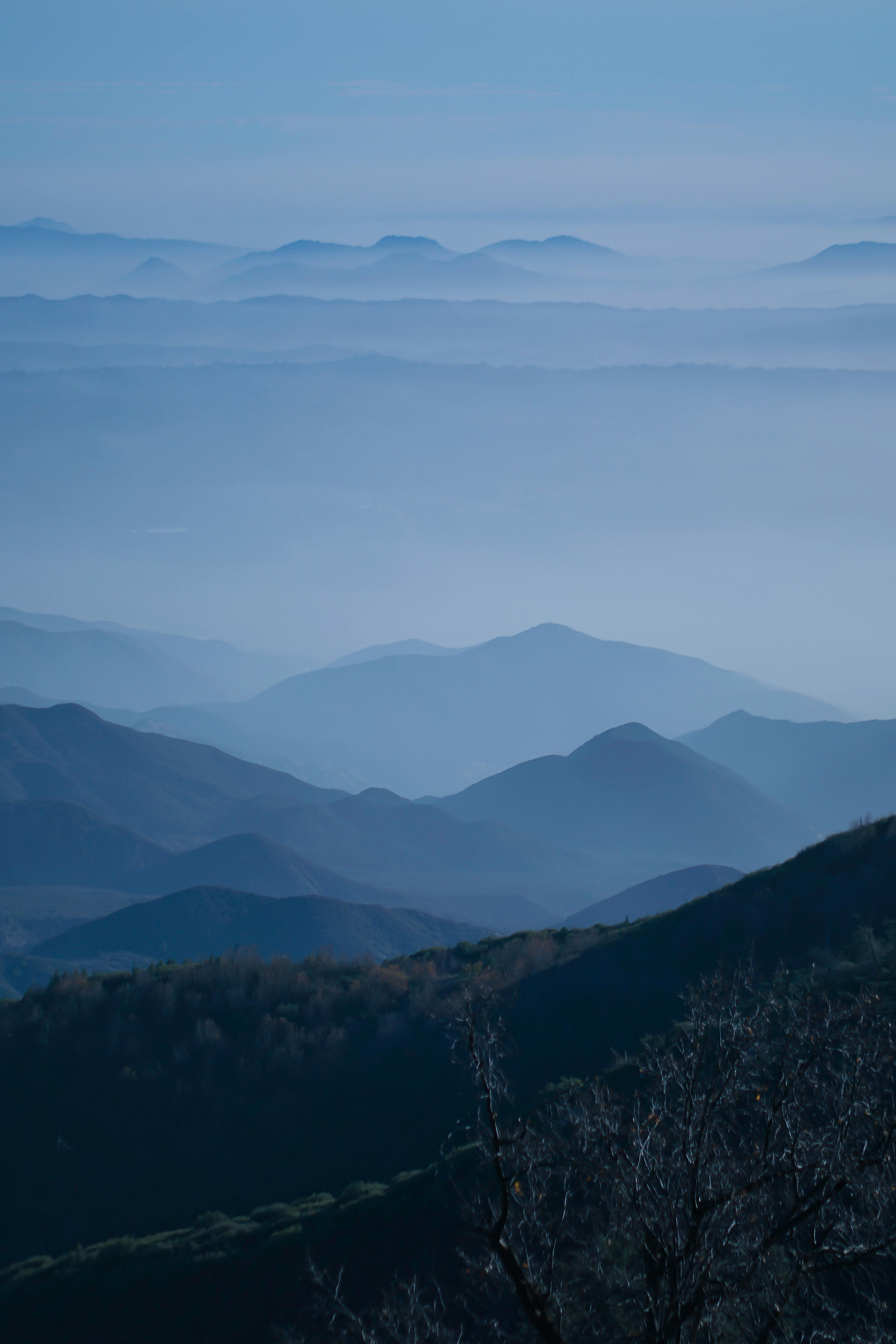 A tranquil scene of blue mist enveloping mountain ranges, creating a peaceful ambiance.