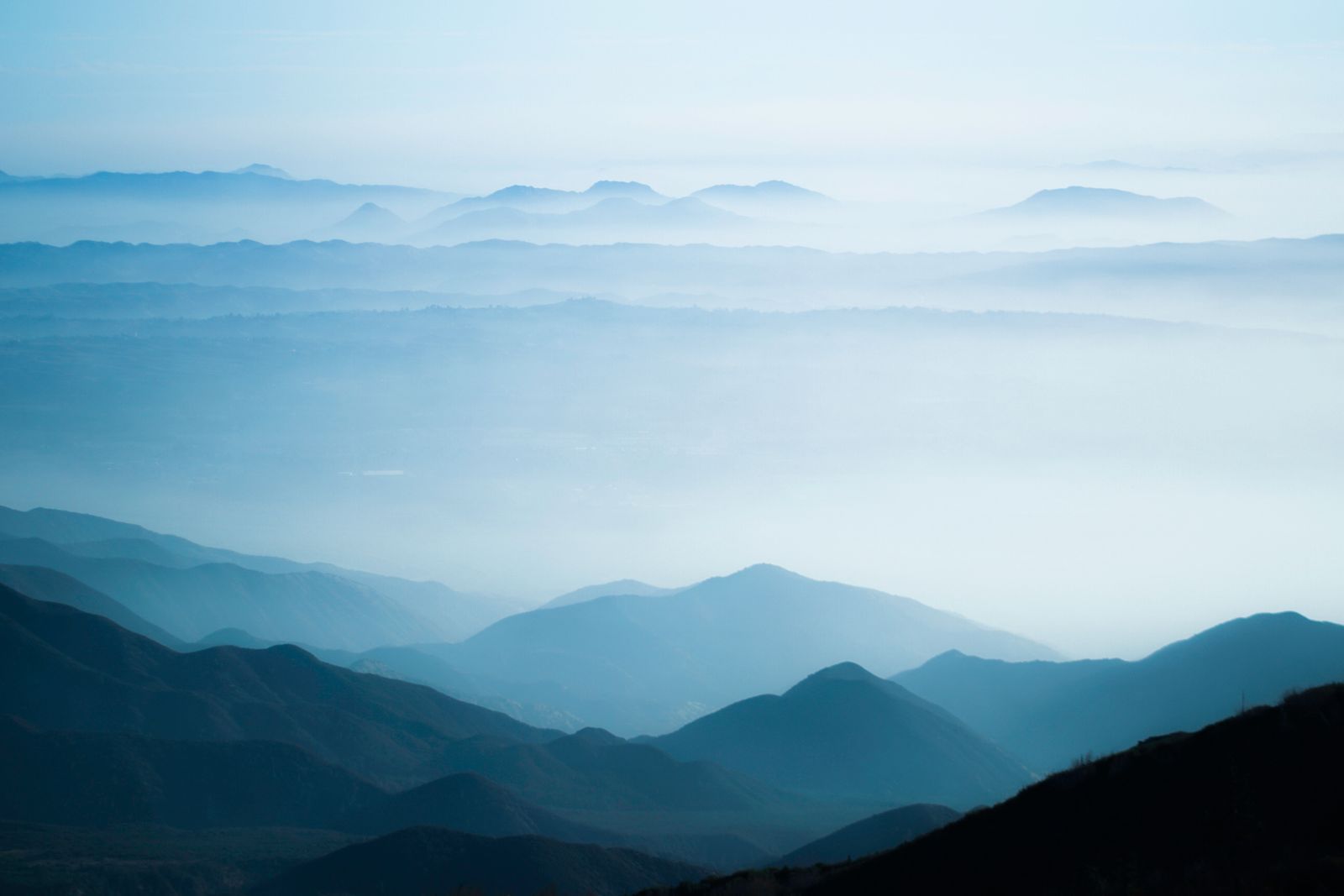 Layered mountain ridges in fog, photo by Daniel Torobekov on Pexels