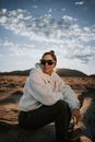 Woman in White Faux Fur Jacket and Black Leggings Sitting in Steppe on Sunny Day