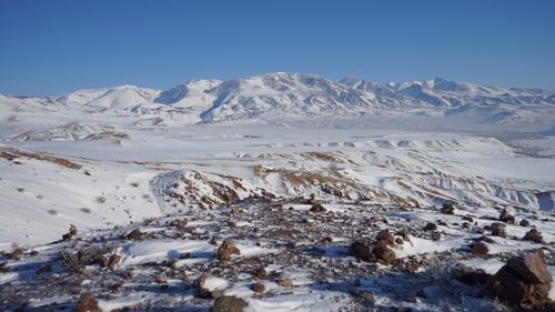 Free Stunning snow-covered mountains under a clear blue sky with rocky foreground Stock Photo
