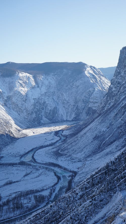 An Aerial Photography of a Snow Covered Mountains Under the Clear Sky