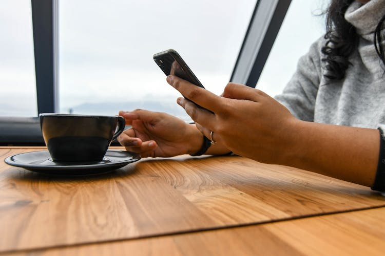 Person Holding Ceramic Cup On Table