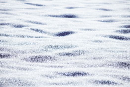 Close-up of a textured snowy surface glistening under bright winter sunlight, showcasing natural patterns.