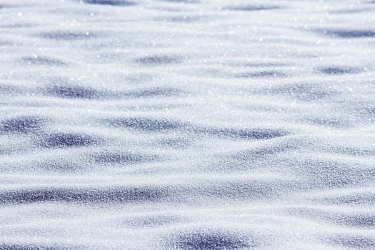 Detailed view of a glistening snow surface capturing the essence of winter with a natural patterning.
