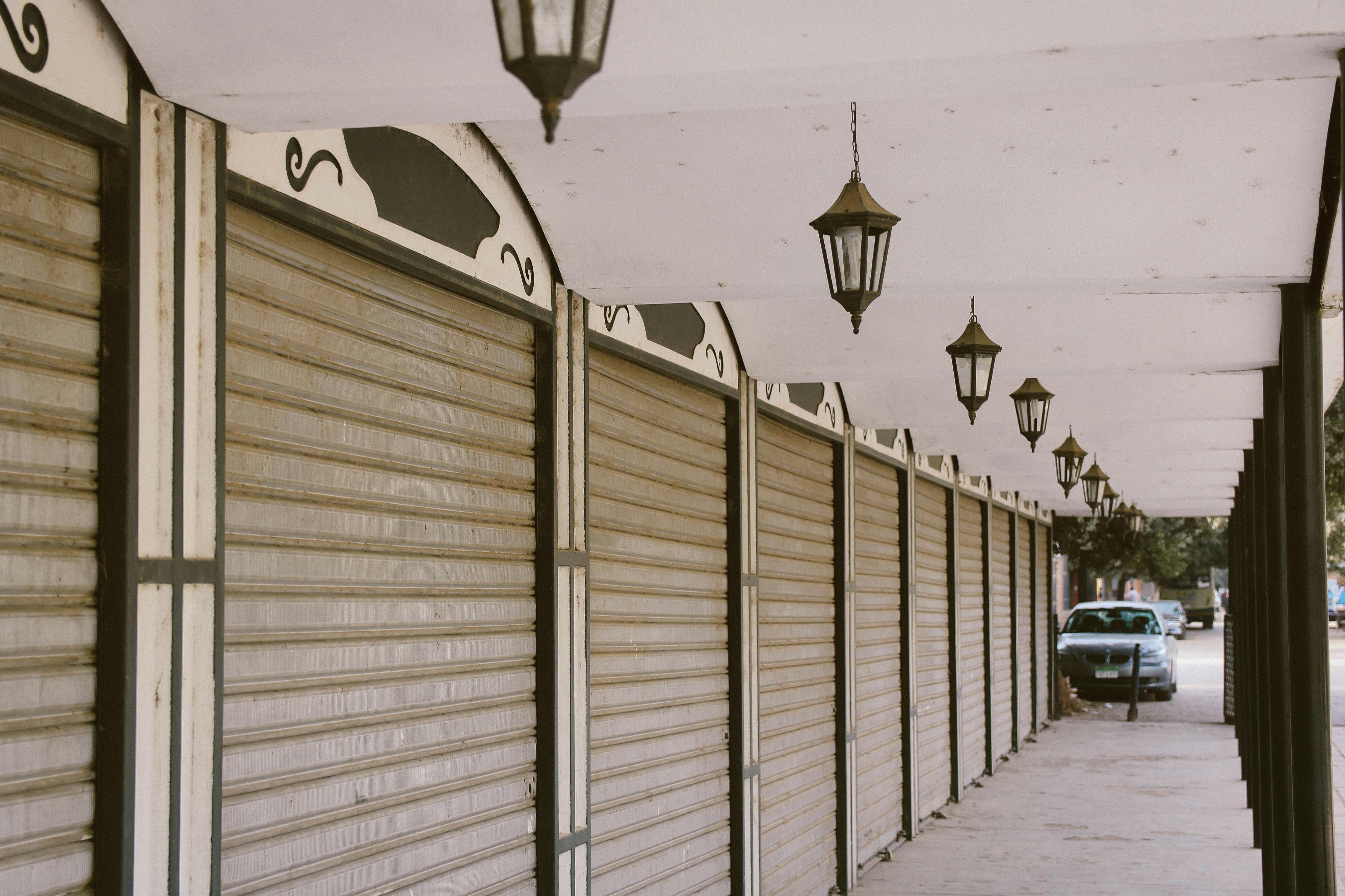 A quiet urban street featuring closed storefronts with decorative lanterns.