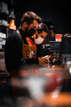 Baristas in face masks working at a coffee shop amid COVID-19 with focus on safety.