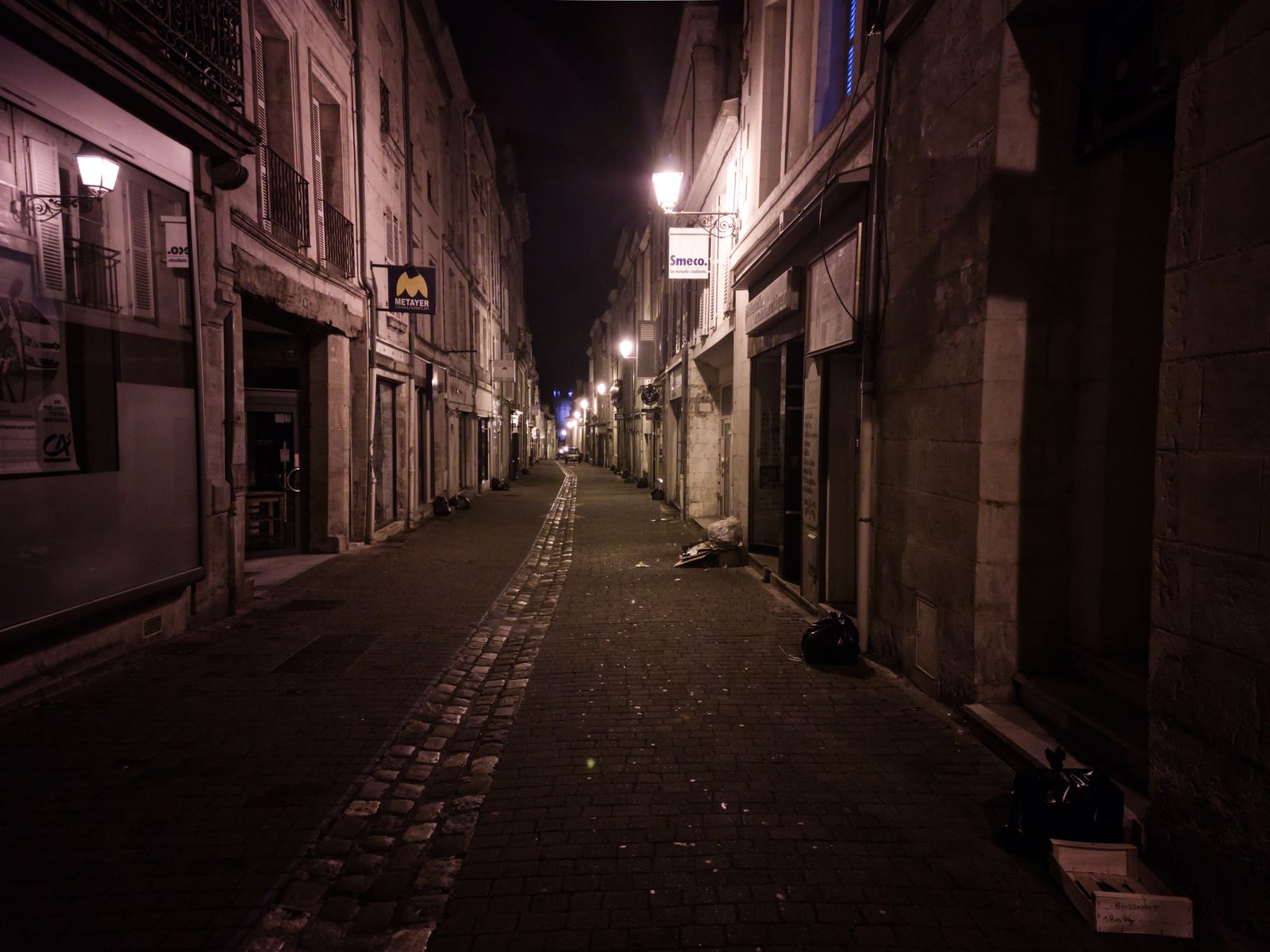 Rue commerçante étroite et déserte la nuit avec pavés et lanternes