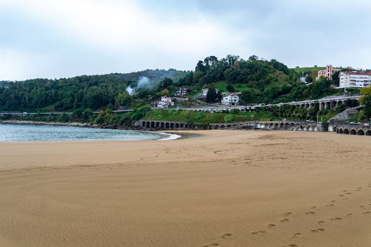 Empty Sandy Beach With Townscape In Background