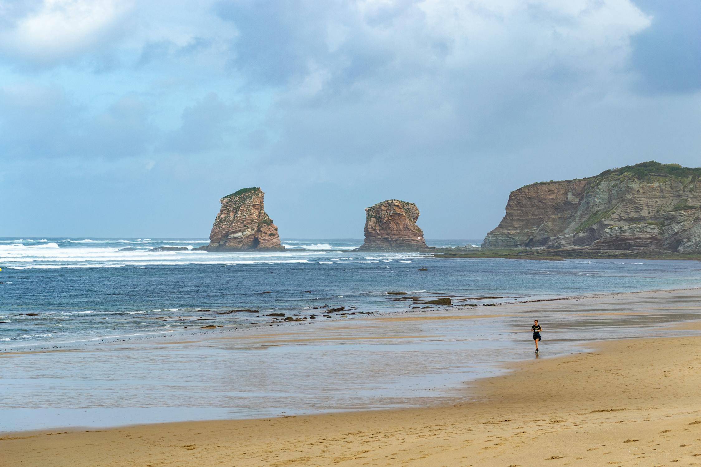 A person jogging at the shore of Hendaya, one of the best beaches in France.