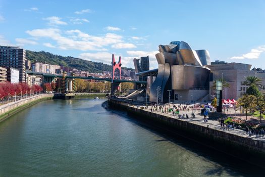 A stunning view of Guggenheim Museum Bilbao alongside a scenic river and urban landscape.
