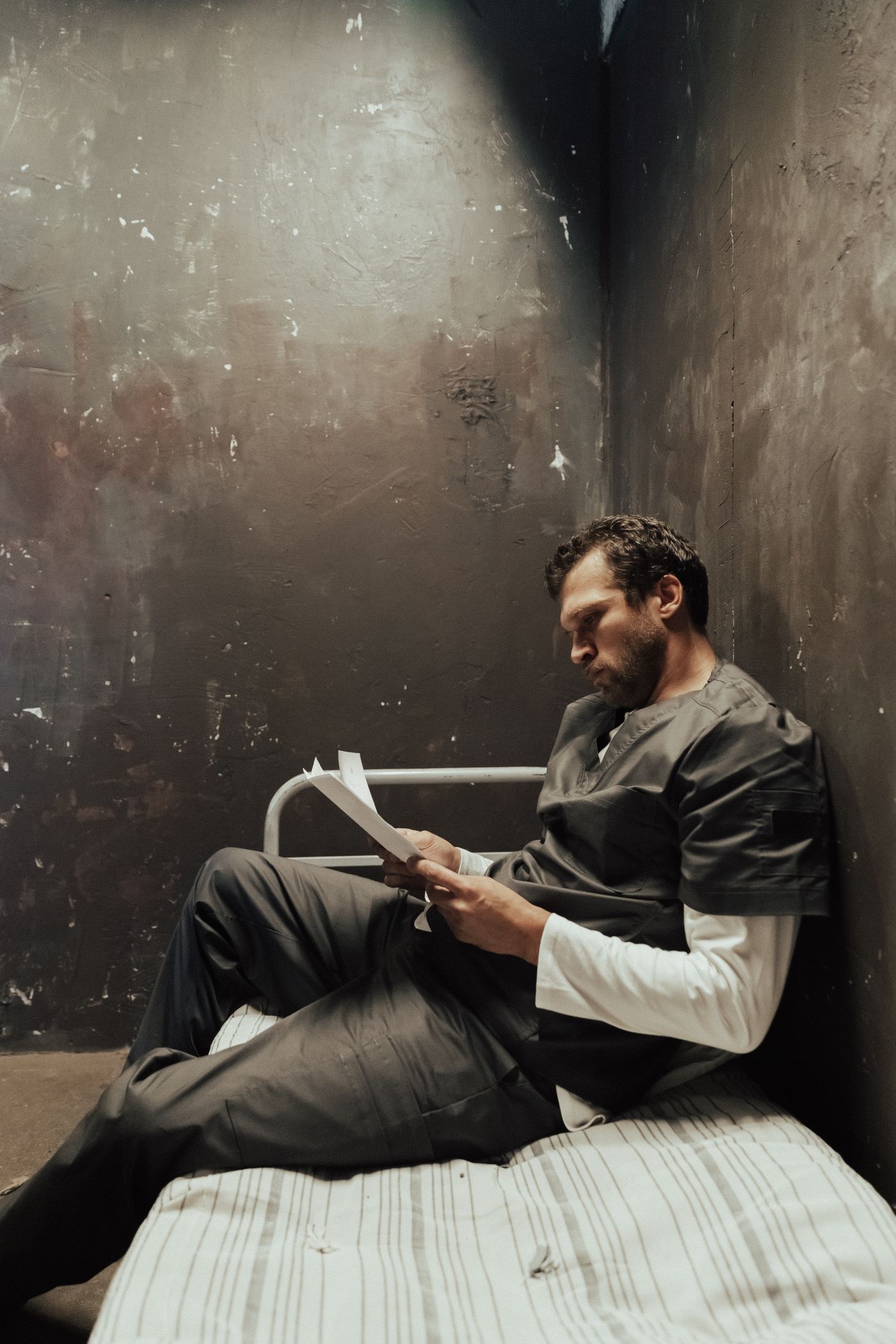 Person reading correspondence while seated inside a cell