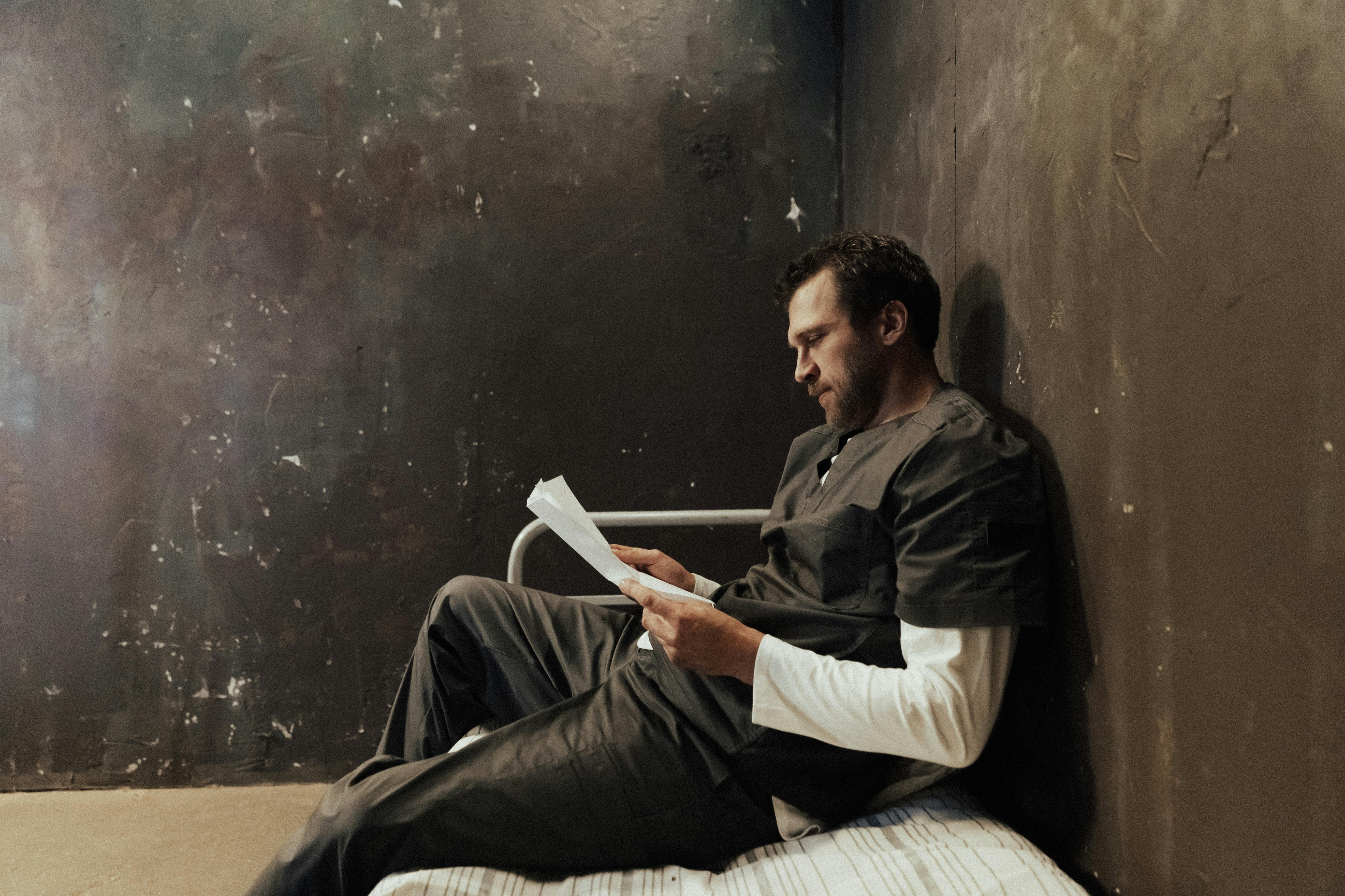 man siting on bed reading a paper