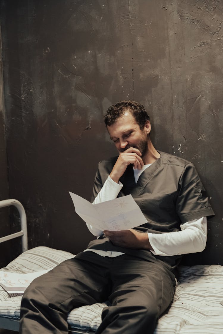 Bearded Man In A Prison Cell Reading A Letter