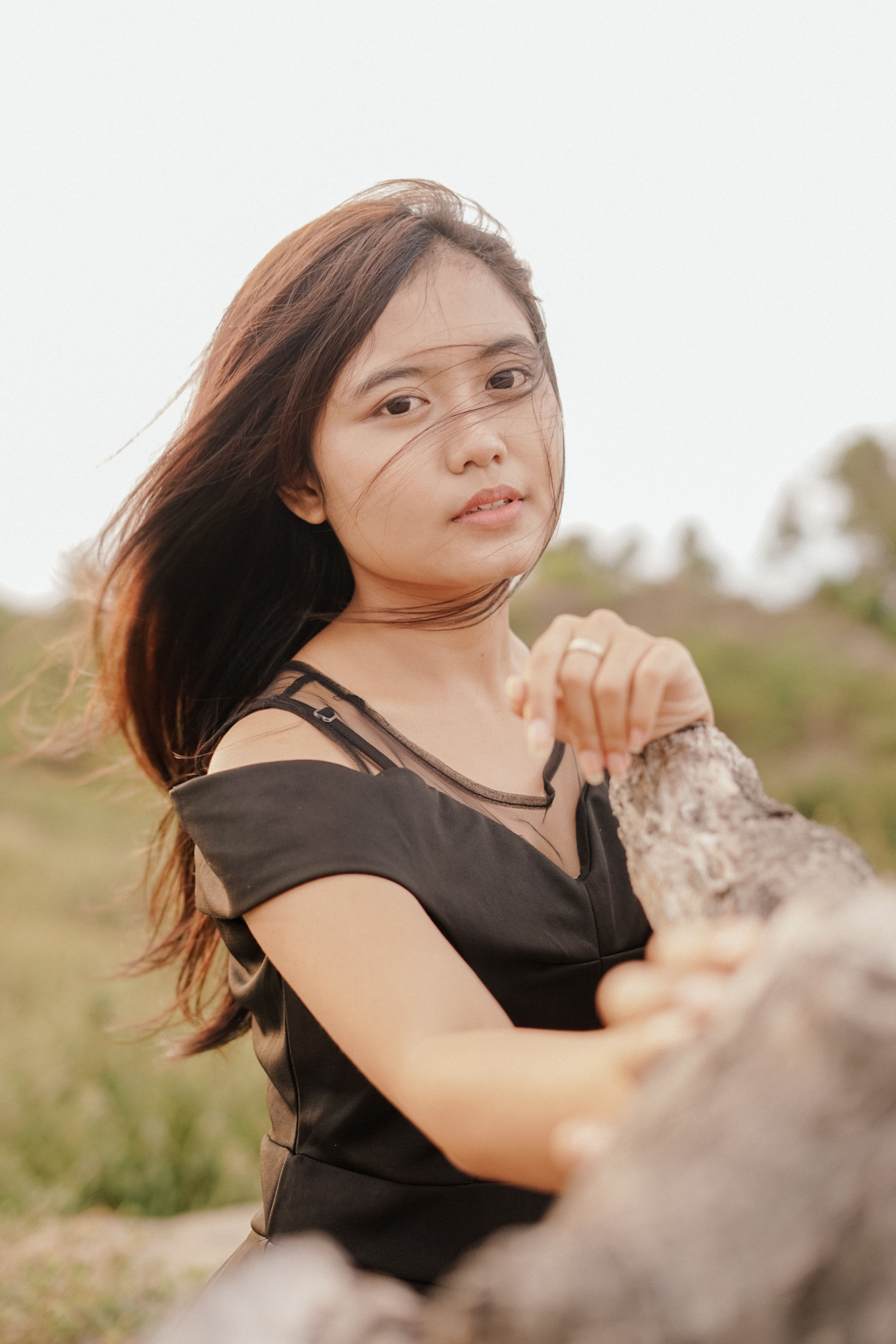 A young Asian woman poses outdoors in Yogyakarta, Indonesia wearing a black dress.