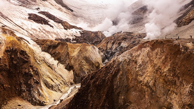 Dramatic volcanic landscape in Kamchatka with steam rising from the earth.